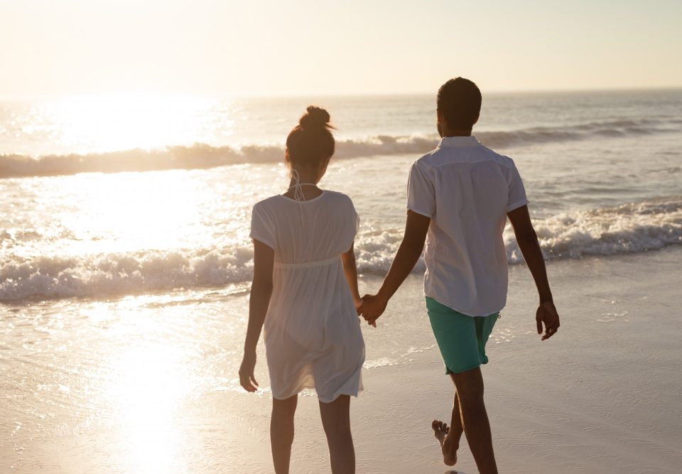 couple walking together hand hand beach