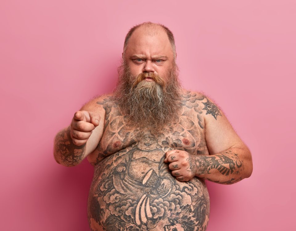 angry offended overweight man keeps hand big naked tummy blames you hears offensive words about himself has tattooed body long thick beard made keep diet